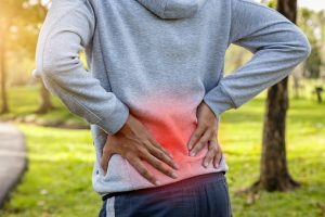 Sport man suffering from backache at park outdoors, Lower back pain concept